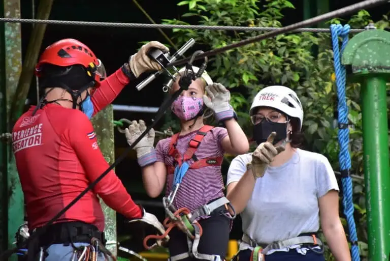 a picture of sky trek arenal zipline operator helping a child to gear up