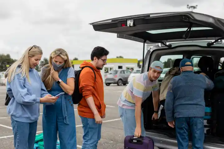 A group of travelers standing in a parking lot ready to get in their shared shuttle.