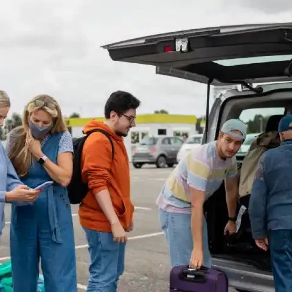 A group of travelers standing in a parking lot ready to get in their shared shuttle.