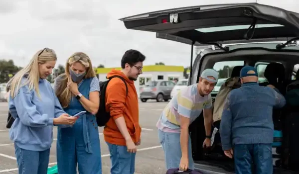 A group of travelers standing in a parking lot ready to get in their shared shuttle.